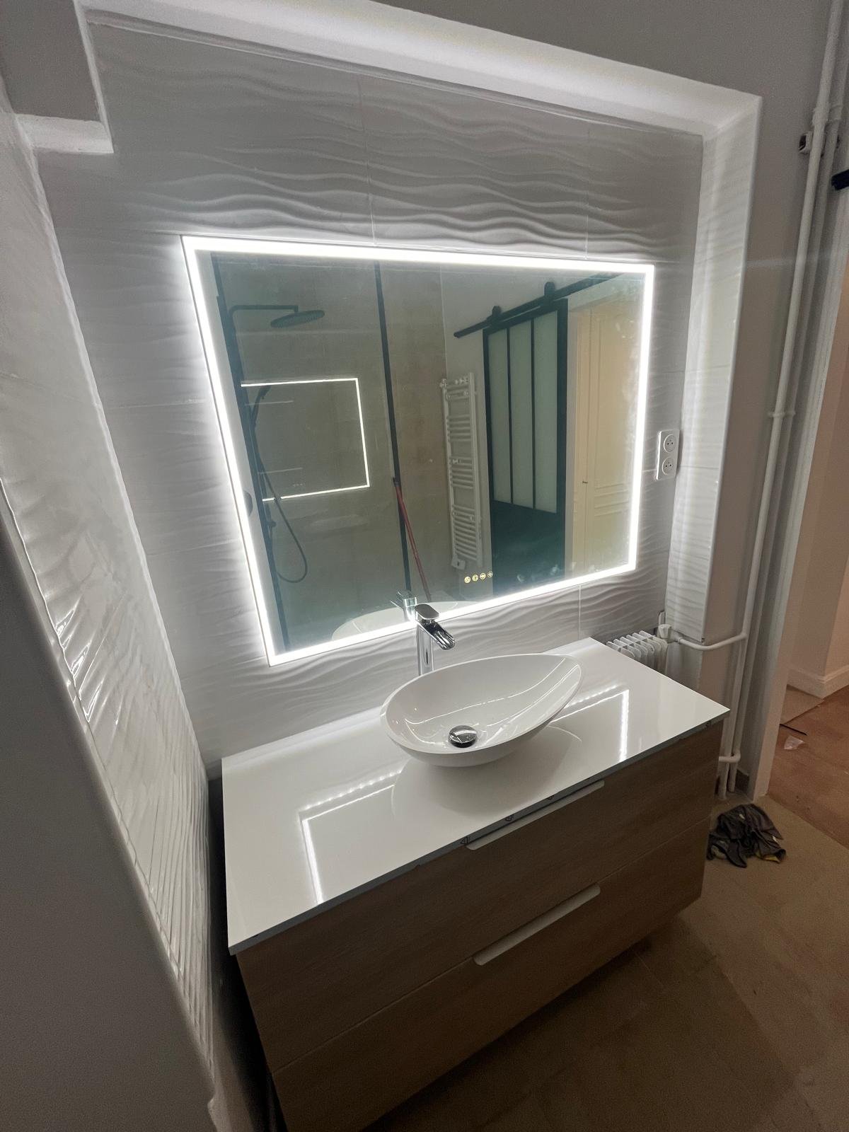 Vasque et miroir lumineux dans une salle de bain rénovée